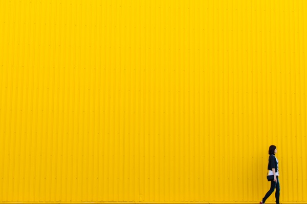 Woman walking in front of yellow wall